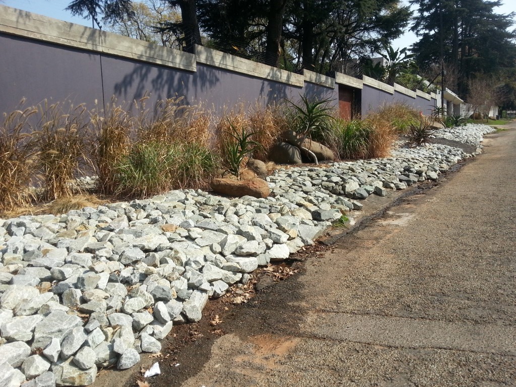 Rocks on the front of the neighboring house making it hard to even get near the front wall
